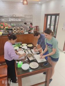 un gruppo di donne che si siedono intorno a un tavolo a preparare il cibo di Tam Coc international friends a Ninh Binh