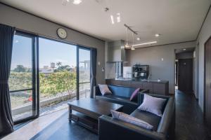 sala de estar con sofá y mesa en プライベートハウス ぅーじ家, en Hanagusuku