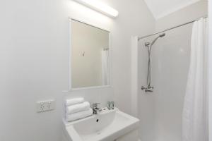 a white bathroom with a sink and a mirror at Reflections Ballina - Holiday Park in Ballina