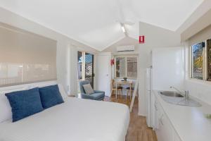 a bedroom with a white bed and a sink at Reflections Ballina - Holiday Park in Ballina +26 photos