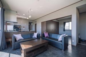 a living room with a blue couch and a table at プライベートハウス ぅーじ家 in Hanagusuku