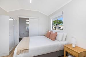a white bedroom with a large bed and a window at Reflections Ballina - Holiday Park in Ballina
