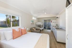 a bedroom with a white bed and a kitchen at Reflections Ballina - Holiday Park in Ballina