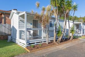 una casa blanca con palmeras delante en Reflections Ballina - Holiday Park, en Ballina