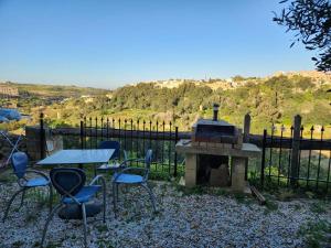 un patio con mesa, sillas y chimenea en Best Relax in the best part of Gozo your own bedroom with Ensuite Toilet and Shared Pool Bed and Breakfast en Għajn il-Kbira