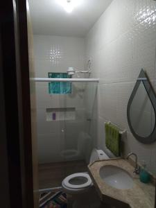 a bathroom with a sink and a toilet and a mirror at Casa do Deca Toledo - 500 metros do Centro Histórico in Paraty