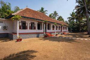 a house with a palm tree in front of it at Kuttanad Kayak Club by Lexstays in Alleppey
