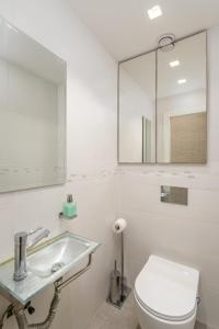 ein Badezimmer mit einem Waschbecken, einem WC und einem Spiegel in der Unterkunft Modern black & white by SeaU TLV in Tel Aviv