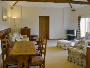 a living room with a table and chairs and a tv at The Cowshed in Blofield