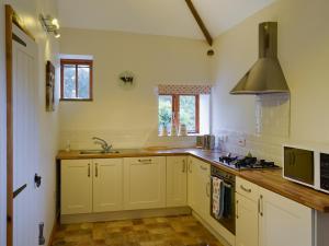 a kitchen with white cabinets and a sink and a stove at The Cowshed in Blofield