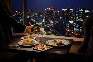 a person pouring wine into a table with plates of food at InterContinental Tokyo Bay by IHG in Tokyo