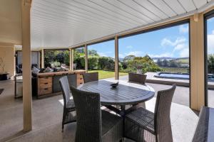 a dining room with a table and chairs and a kitchen at Reinga Retreat - Kerikeri Holiday Home in Kerikeri