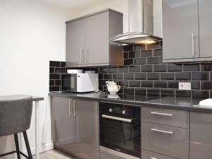 a kitchen with stainless steel appliances and black tiles at The Hideaway in Crieff