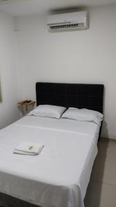 Cama blanca con cabecero negro y sábanas blancas en Hotel Noz INN, en Villavicencio