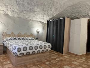 1 dormitorio con 1 cama grande en una pared de piedra en Casa Cueva en Entorno Tranquilo., en Murcia