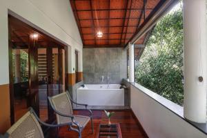 La salle de bains est pourvue d'une baignoire, d'une table et de chaises. dans l'établissement Vythiri Resort, à Vythiri