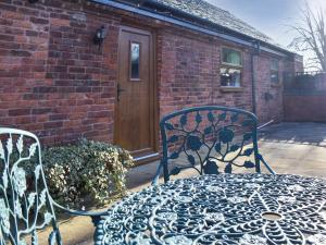 a wrought iron table and chairs in front of a brick building at Brookside Cottage - Uk42869 in Burntwood