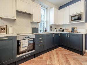 Skye House في بيكويل: مطبخ مع الدواليب الزرقاء والاجهزة البيضاء