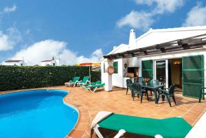 a patio with a pool and chairs and a house at Jomar in Cala en Bosc