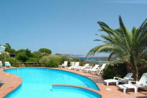 uma piscina com cadeiras brancas e uma palmeira em LH Porto Rafael Altura Resort em Palau