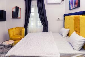 ein Schlafzimmer mit einem Bett und einem gelben Stuhl in der Unterkunft Elegant 1-Bed With Unlimited Internet + 24hrs POWER in Lagos