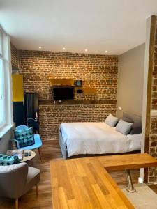 a bedroom with a bed and a brick wall at My Little Home - Le Vieux Lille de Rousseau in Lille