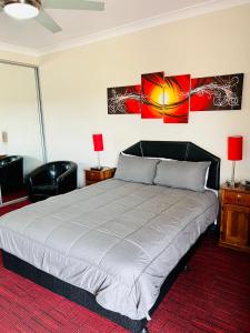 ein Schlafzimmer mit einem Bett, zwei Lampen und einem Stuhl in der Unterkunft Mirambeena Motel in Whyalla