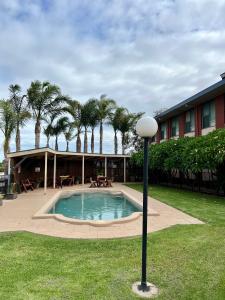 einem Pool vor einem Gebäude mit Palmen in der Unterkunft Mirambeena Motel in Whyalla