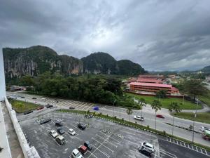 a parking lot with cars parked in front of mountains at HASSMA Studio Apartment at Kompleks Mutiara GM in Gua Musang