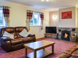 a living room with a leather couch and a fireplace at Gwynfan Bungalow in Nantmel