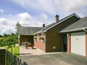 a brick house with a patio in front of it at Gwynfan Bungalow in Nantmel