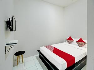 a bedroom with a bed with a red and white blanket at Super OYO 92433 Sirih Gading Family Guest House in Tulungagung