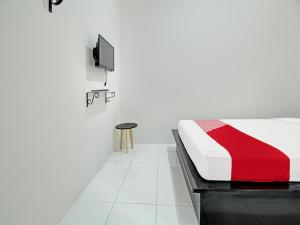 1 dormitorio con 1 cama y TV en la pared en Super OYO 92433 Sirih Gading Family Guest House en Tulungagung