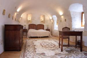a bedroom with a bed and a desk and a piano at Maison des Sarrasins in Beynac-et-Cazenac