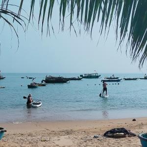 2 personnes sur des planches de surf dans l'eau sur une plage dans l'établissement Chamisland Hanhly homestay, à Hội An