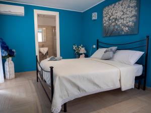 Schlafzimmer mit einem Bett mit blauer Wand in der Unterkunft Flower House in Santo Stefano di Camastra