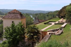 a building on a hill next to a river at Maison des Sarrasins in Beynac-et-Cazenac