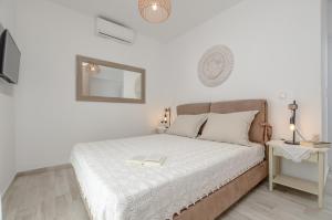 um quarto branco com uma cama e um espelho em Naxian Wave Seaside Villa em Mikri Vigla