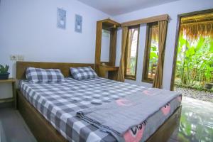 a bedroom with a bed with a blue and white checked blanket at Tastura Homestay in Praya