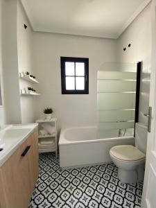 a white bathroom with a tub and a toilet at PINAR 10 in Chiclana de la Frontera