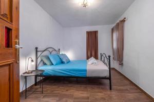 een slaapkamer met een bed met blauwe lakens en een tafel bij Beautiful historic house in Koskinou