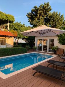 a swimming pool with an umbrella and two lounge chairs at Villa Gloria 2 in Dubrovnik