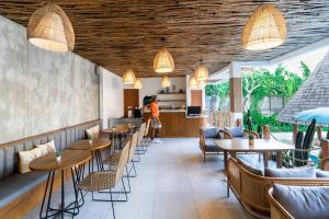 a restaurant with wooden ceilings and tables and chairs at Roomates Hostel Canggu by Ini Vie Hospitality in Canggu