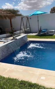 a swimming pool with a swing and an umbrella at Villa Line in Taguermess