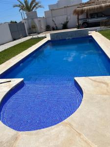a large blue swimming pool in front of a house at Villa Line in Taguermess