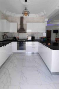 a kitchen with white cabinets and a white tile floor at Villa Line in Taguermess