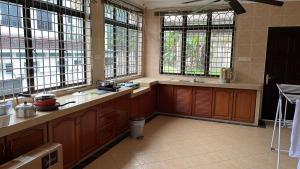 a large kitchen with wooden cabinets and windows at Dino House in Taiping