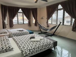 two beds and a hammock in a room with windows at Dino House in Taiping