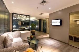 a living room with a couch and a tv on a wall at Silverland Jolie Hotel in Ho Chi Minh City