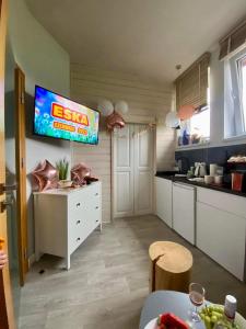 a kitchen with a tv on the wall and a table at Apartament & Spa Rosa in Istebna
